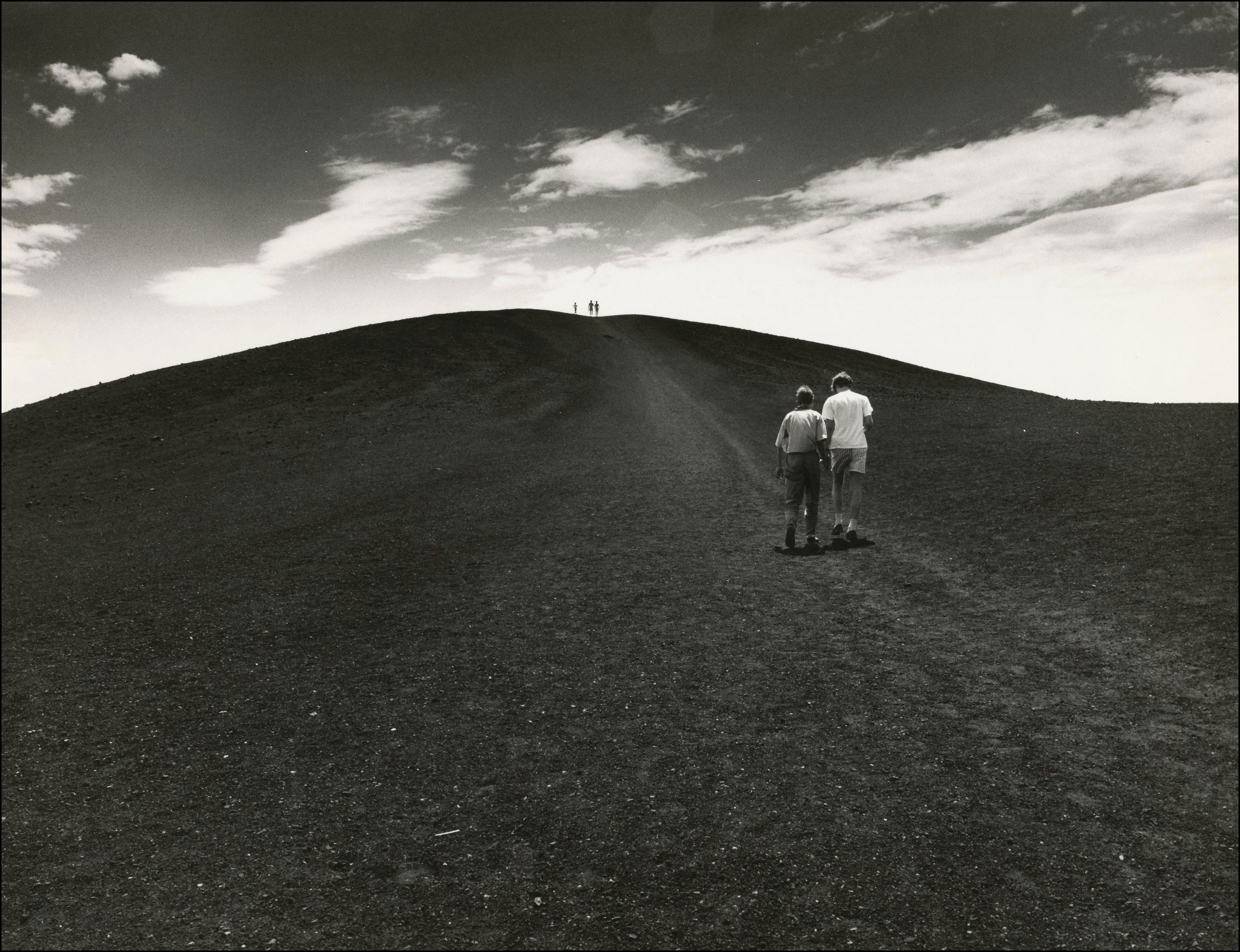 Two people walking on barren surface at Craters of the Moon National Monument