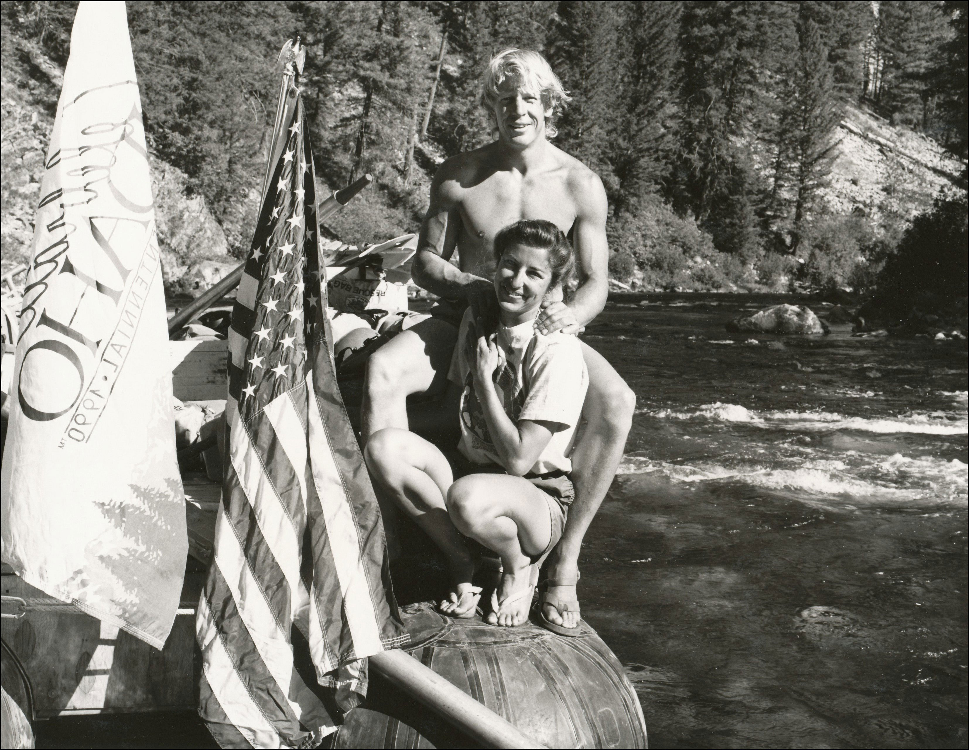 River guide couple on boat with flags in the river