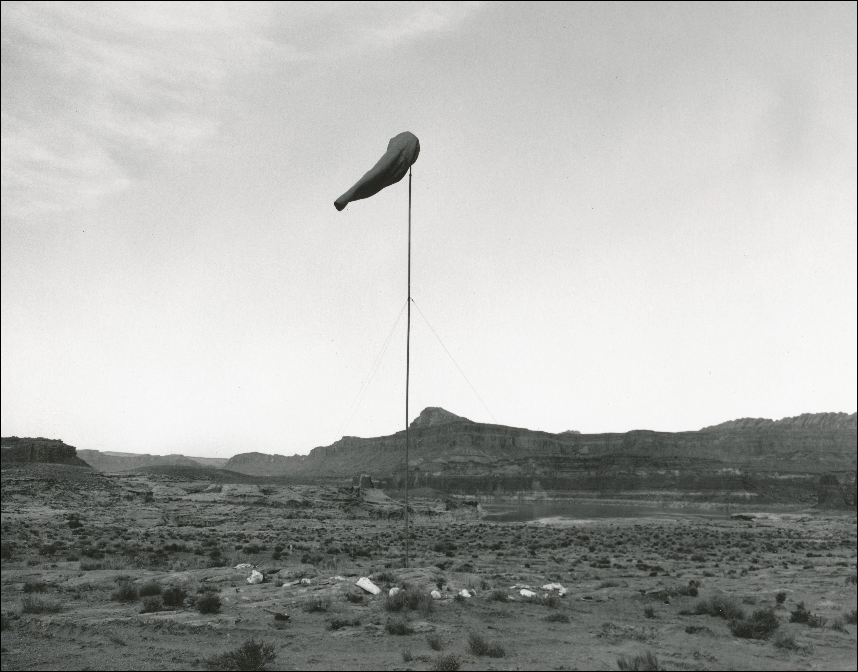 Wind flag in desert with plateaus in background
