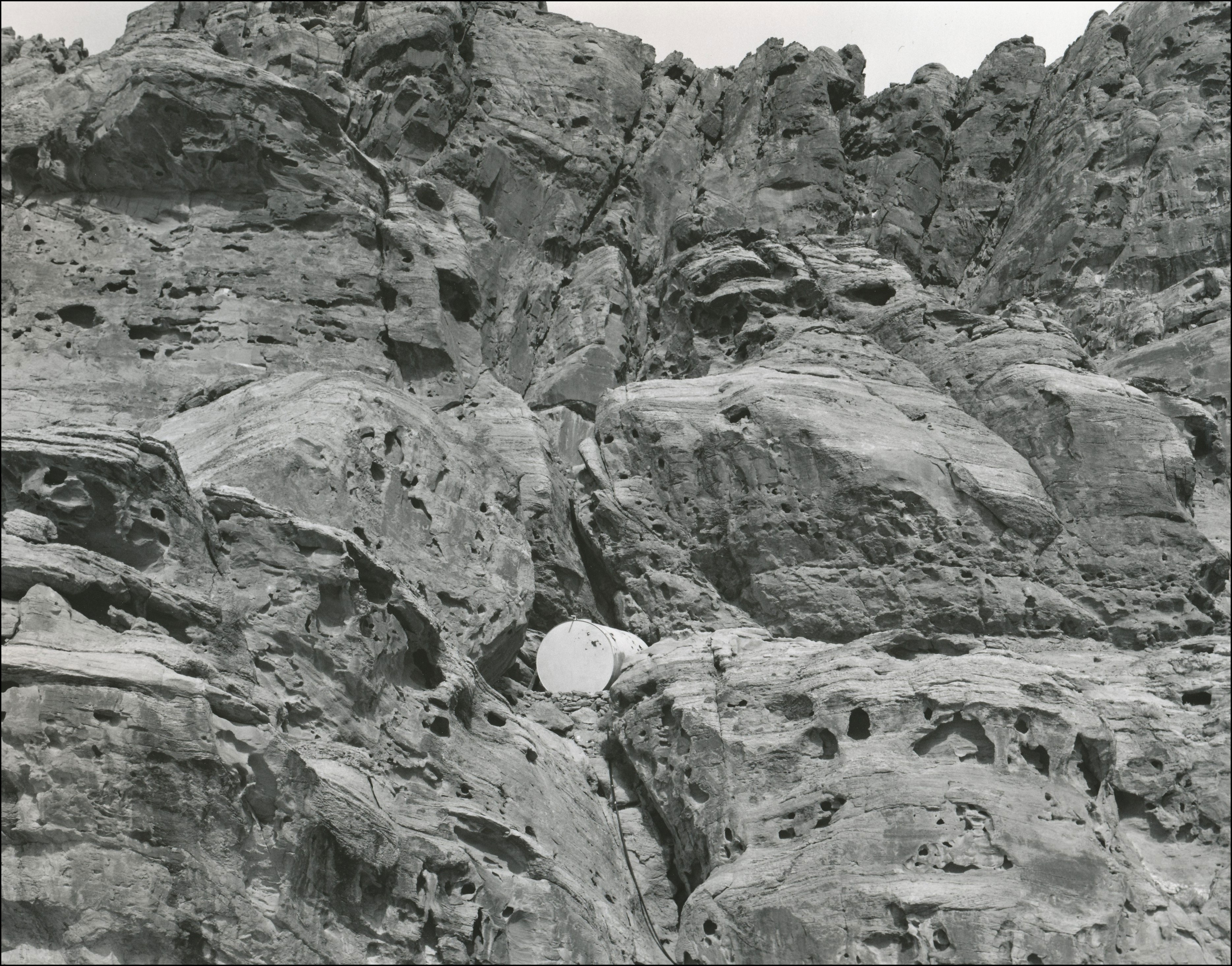Round metal tank up in a crevice in large rocky mountain
