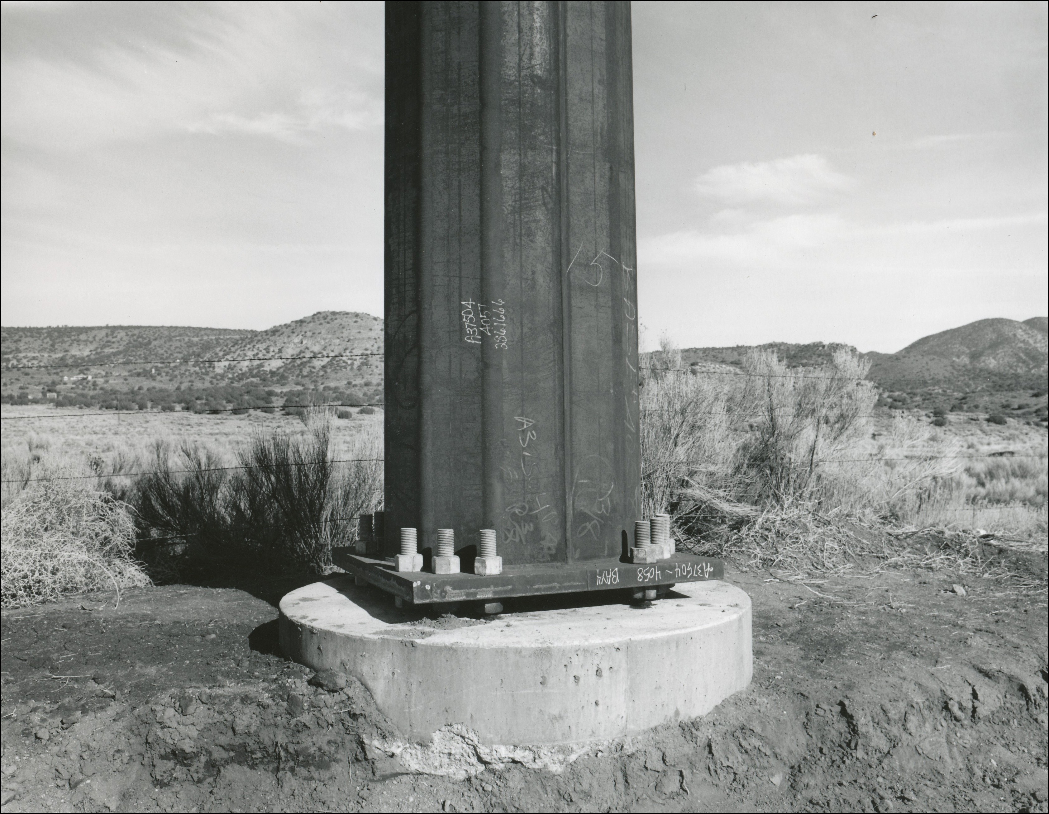 Base of large metal utility pole bolted into cement base