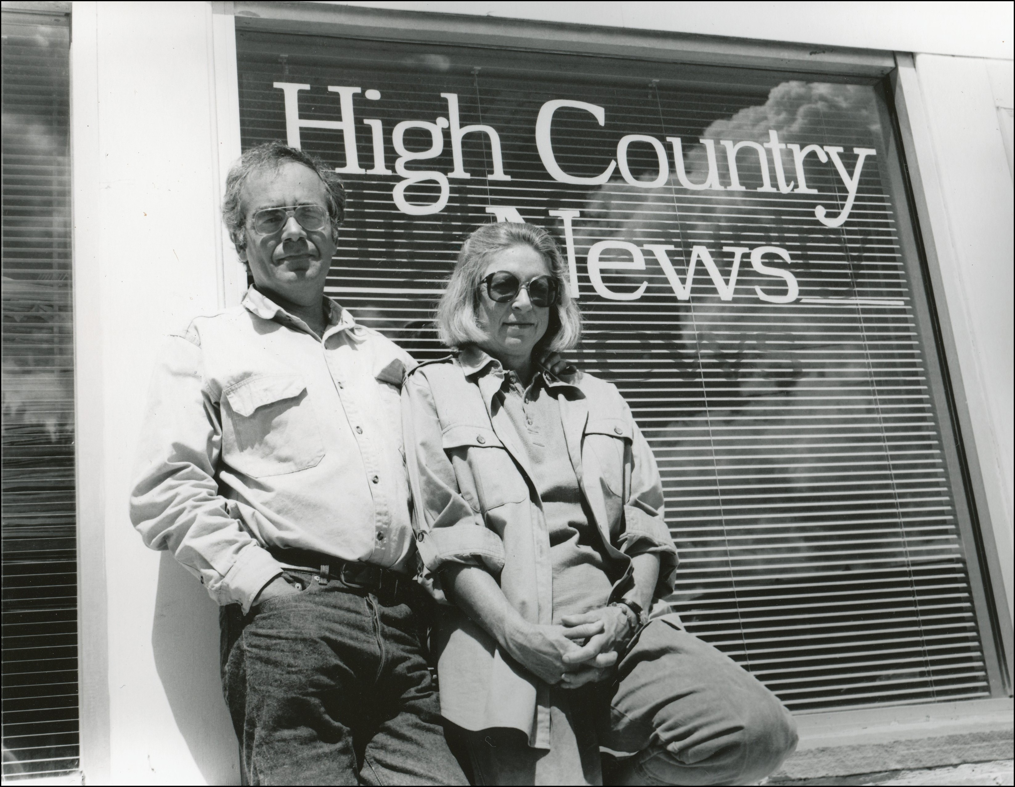 Couple standing in front of window that says High Country News