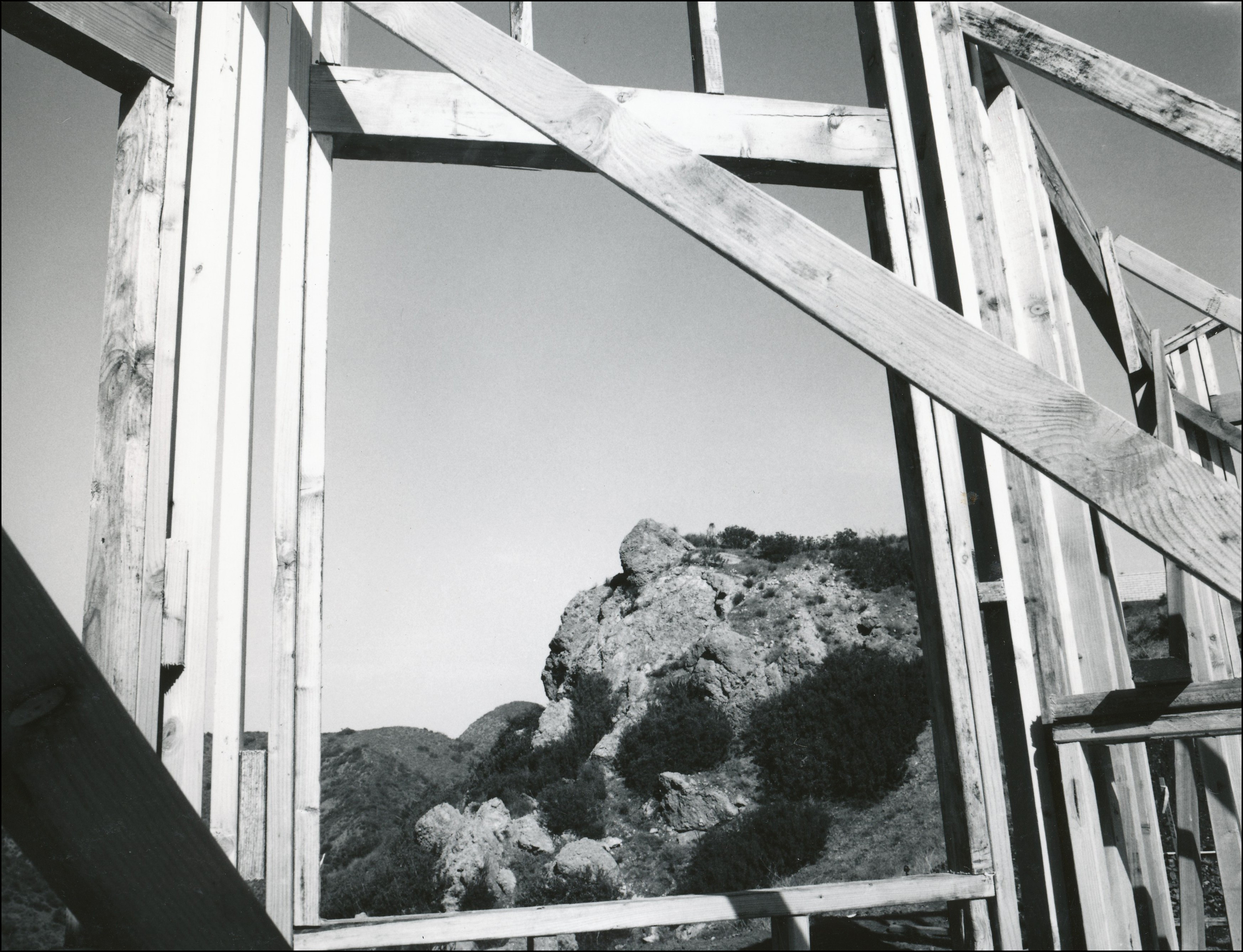 Looking out at a rocky mountain from the inside of a wood house frame