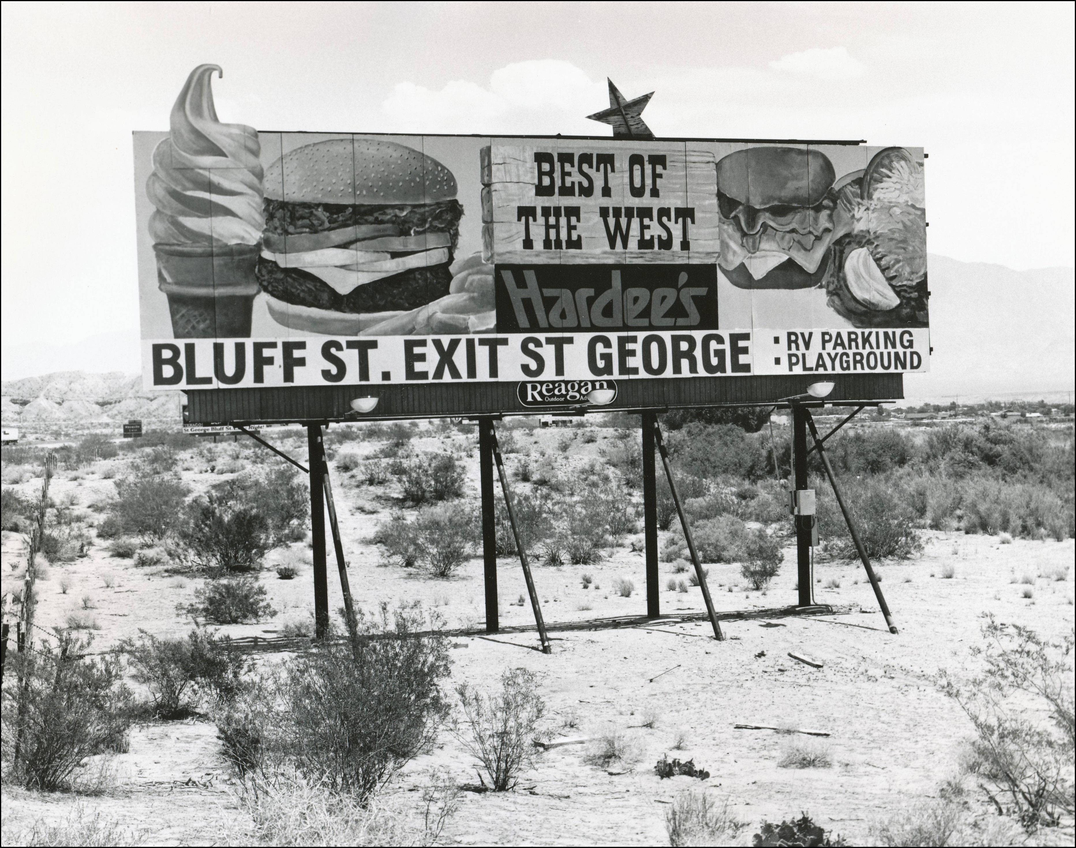 billboard advertising Hardees in St George. Picture of Ice cream cone, burger and sandwich. States that there is RV Parking and a playground