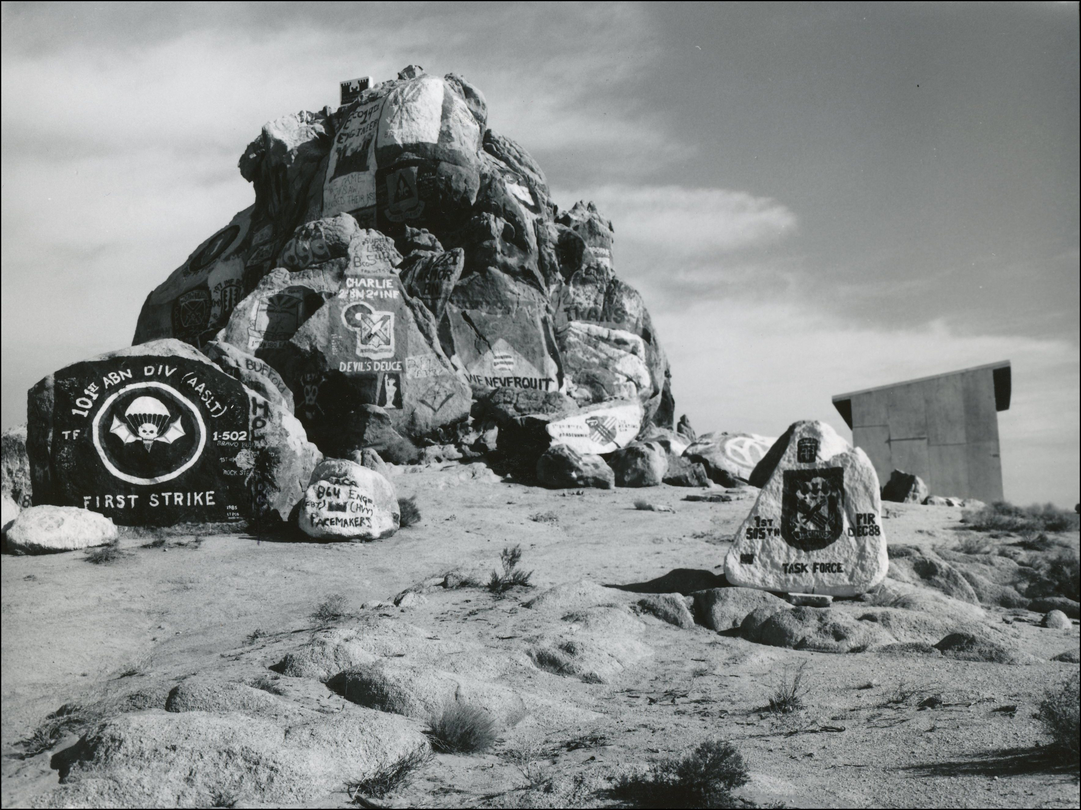 Rock mound and smaller rocks surrounding. Paintings on the rocks of military strikes and other military signage