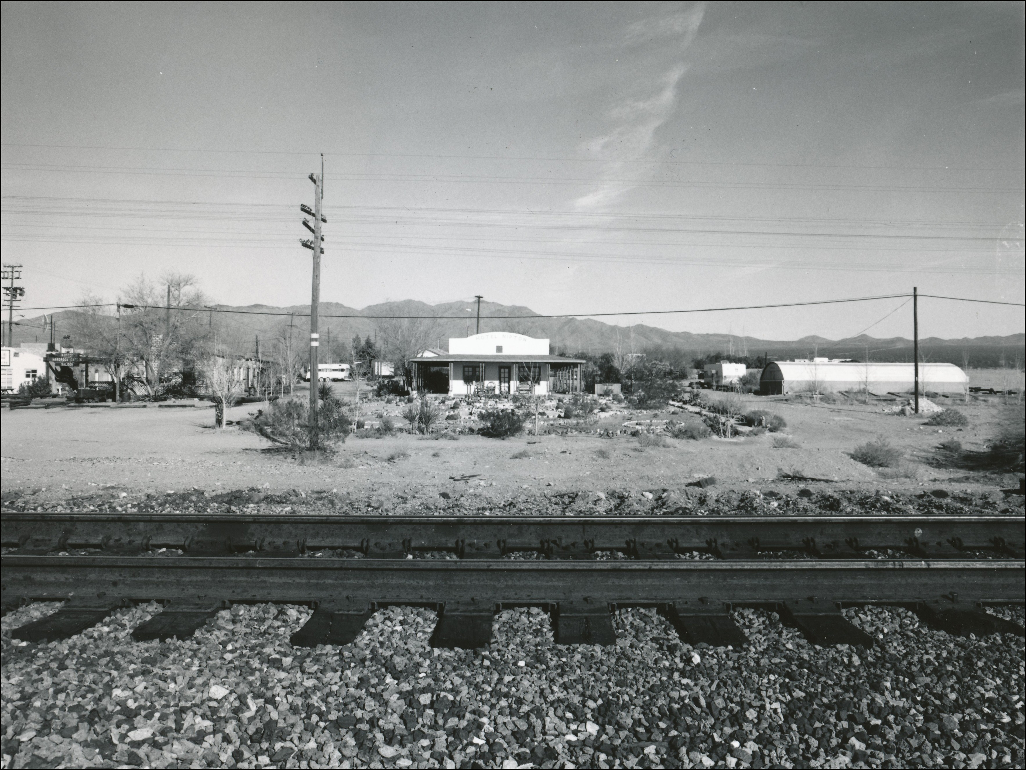 Looking across railroad tracks at an old hotel.